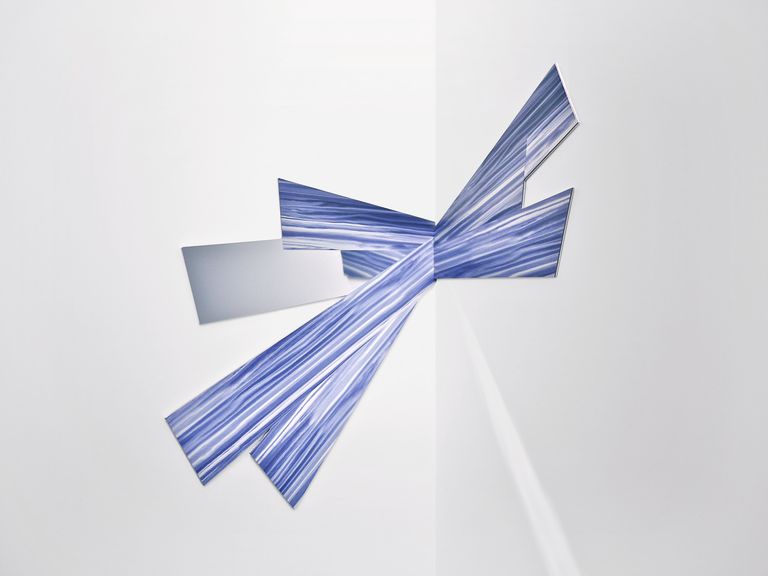 Blue sculpture coming out of the corner of a white room. 