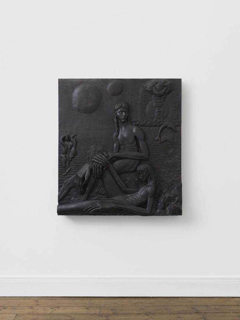 Large dark relief sculpture depicting nude figures in a dramatic scene with celestial elements like moons and clouds in the composition.