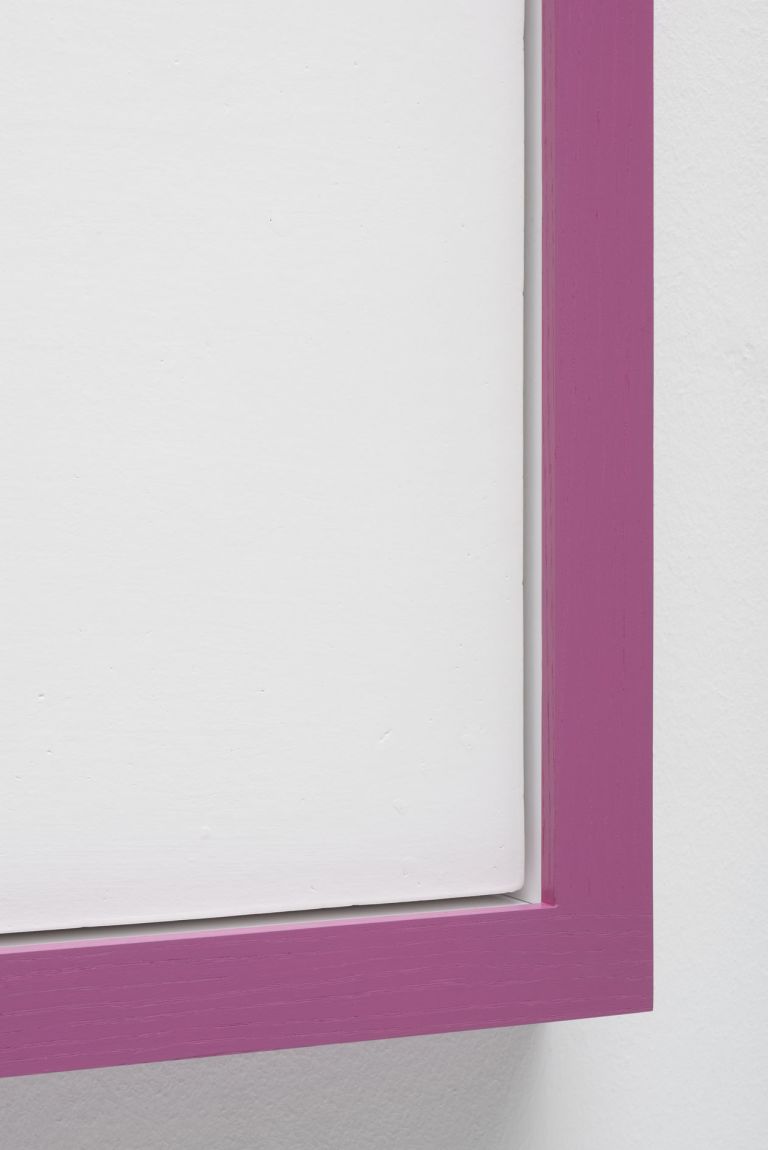 Minimalist white square artwork with pink colored borders mounted on white wall. It features a small black hole near the left edge.