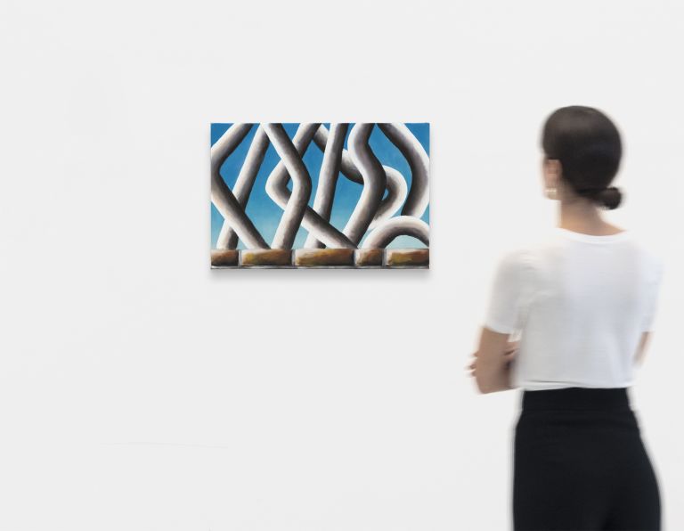 Abstract painting of white intertwining chain-like forms against bright blue sky background, positioned above brown brick foundation