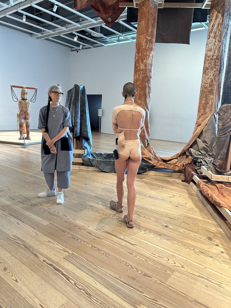 Black-framed display showing text and multiple photographs documenting performance art in various indoor gallery and museum settings.