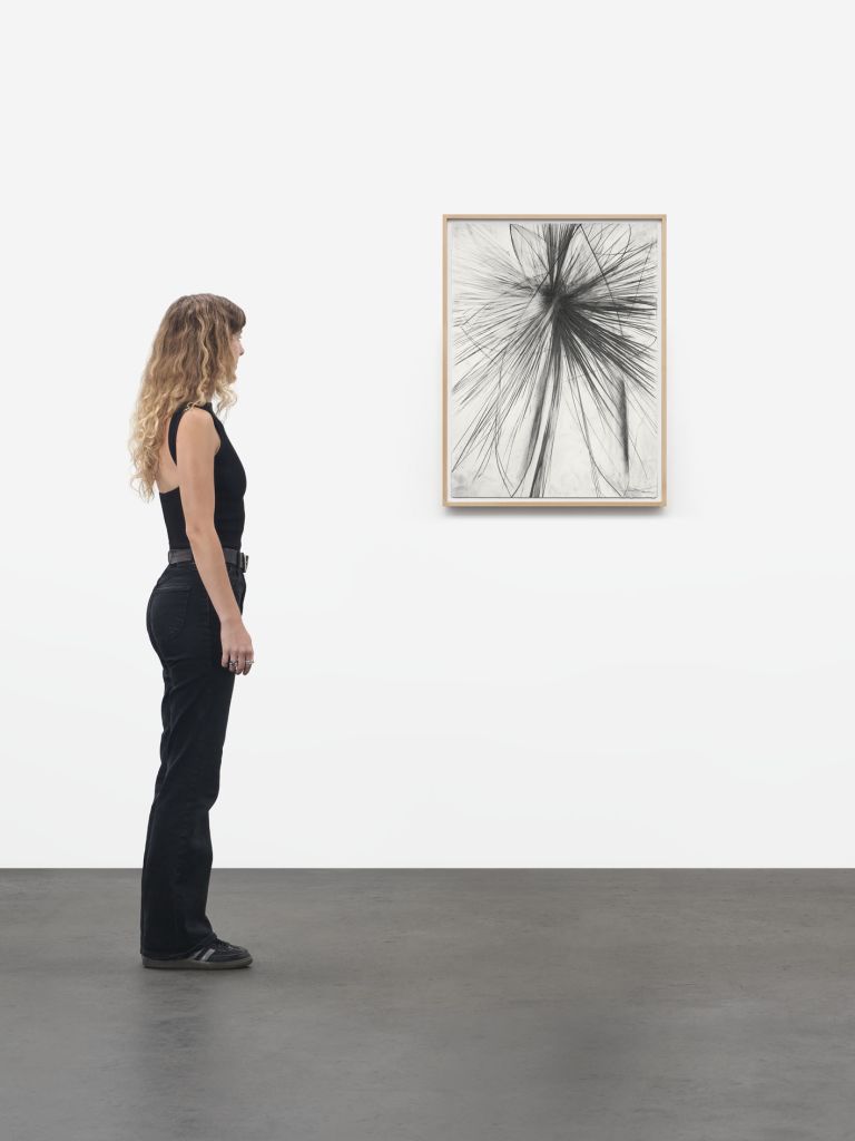 Framed abstract drawing with dense black graphite lines exploding outward in all directions on white