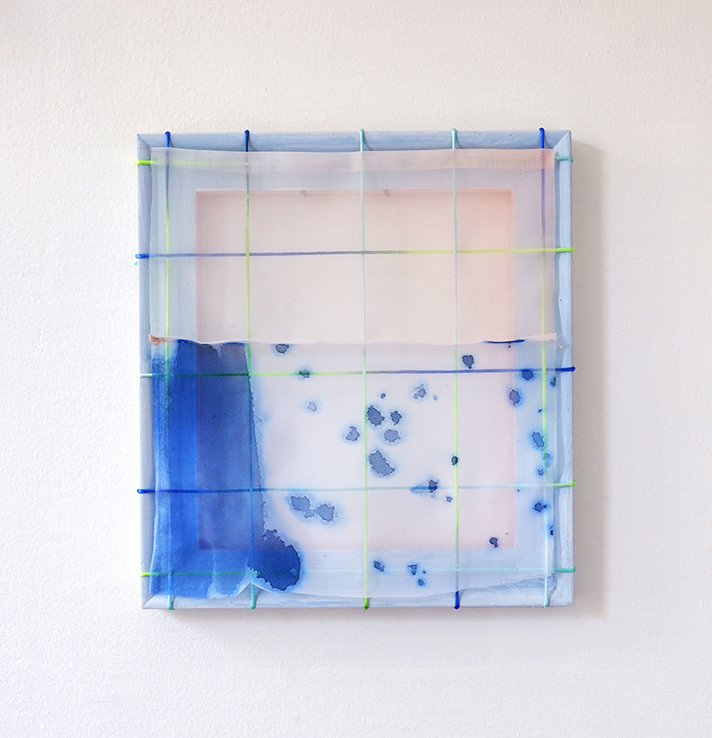 A square abstract artwork with a translucent grid stretched over a wooden frame. The surface shows washes of blue and pink, with darker blue stains scattered across the lower half.