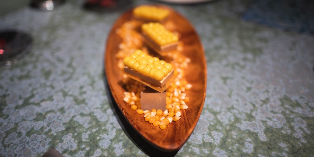 Corn on foie gras on a cracker on a bed of dried corn kernels