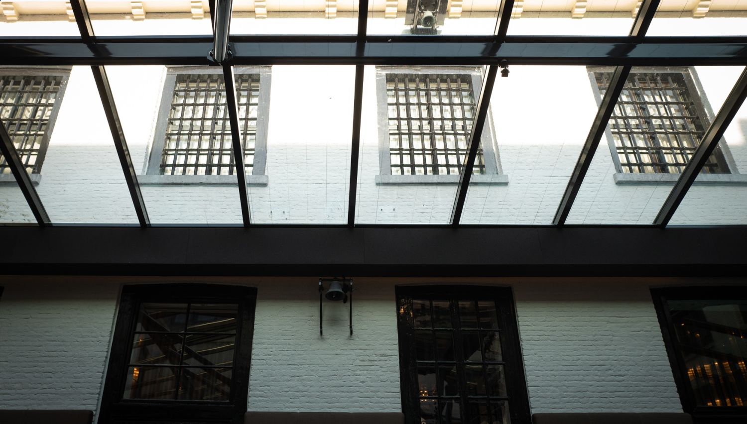 Glass covered courtyard with prison bars on the upper floor windows.