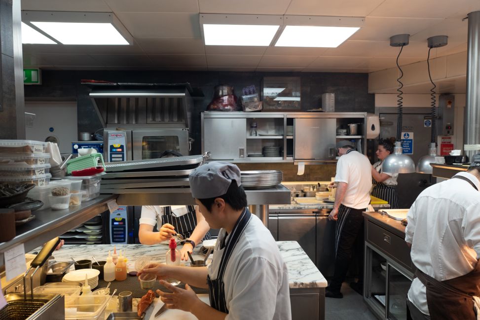 A busy small kitchen with multiple chefs at their stations.