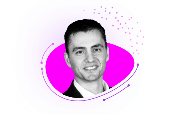Black-and-white headshot of a smiling man in a suit against a bright pink and purple abstract background