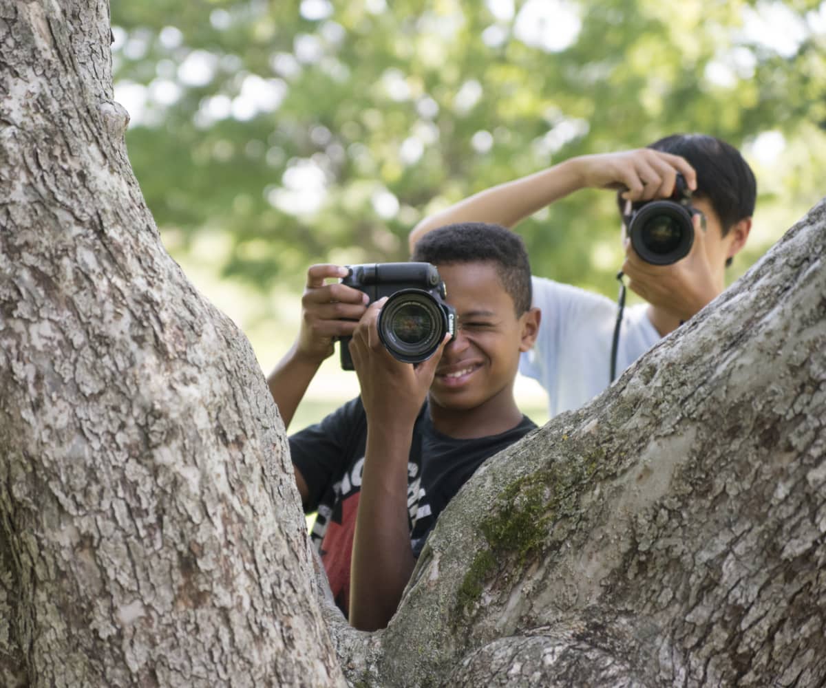Photography camp students taking photo over tree
