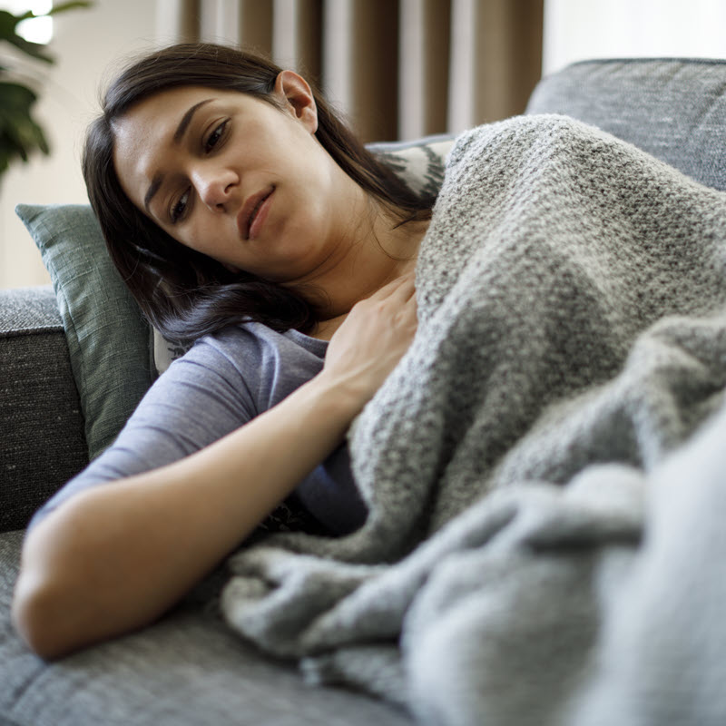 Woman lying on her couch feeling unwell