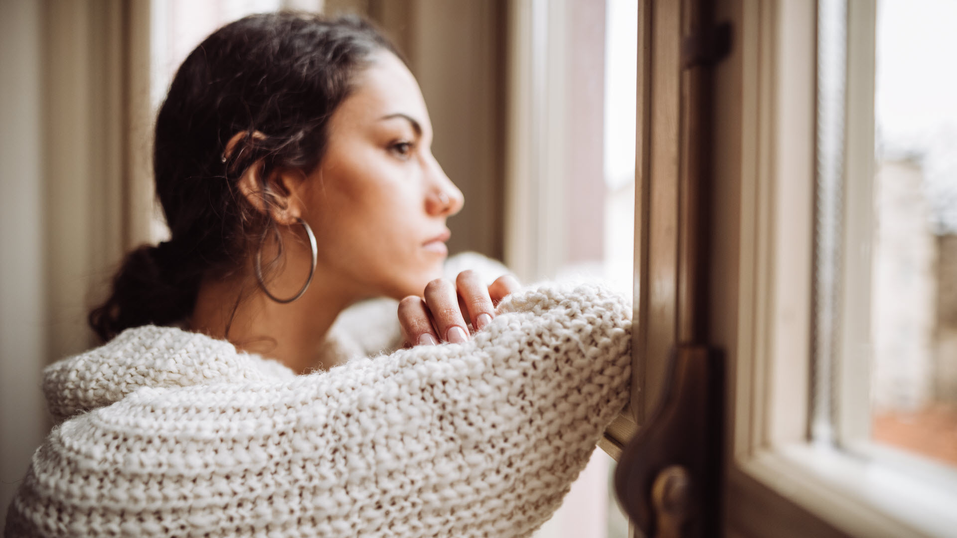 woman staring out the window of her house
