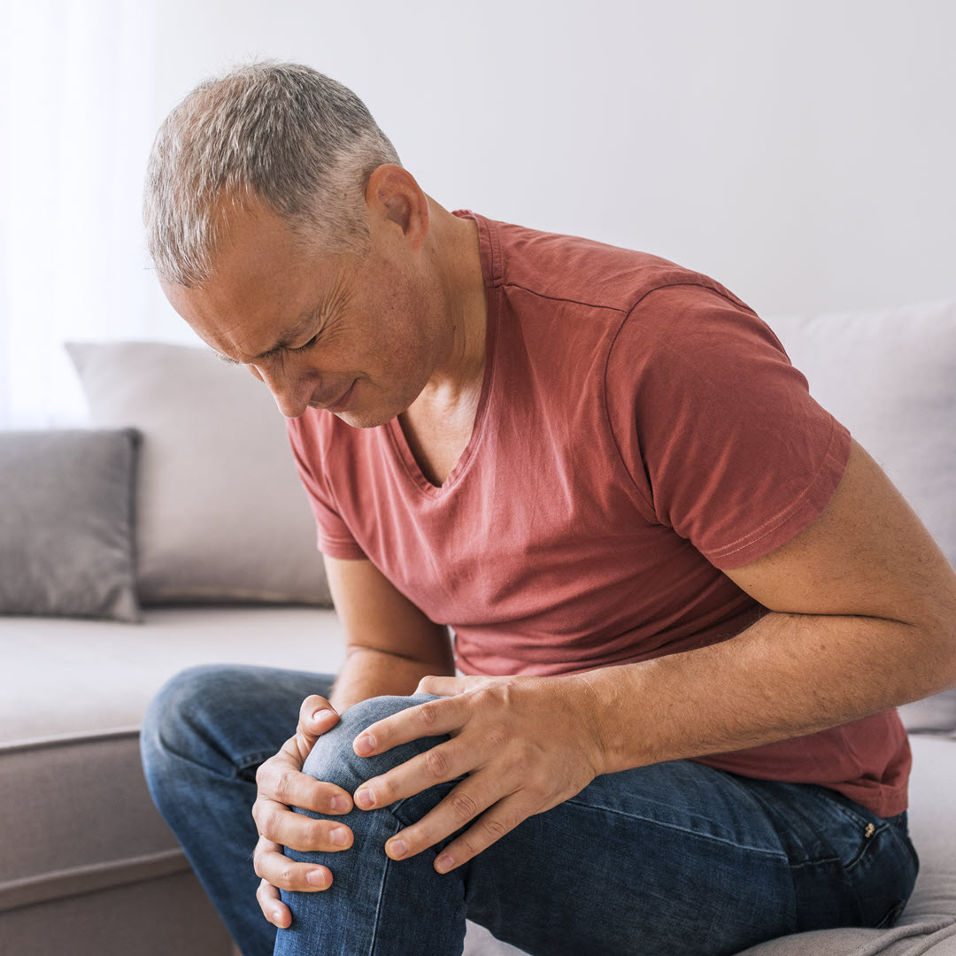 Man with sore knee sitting on couch