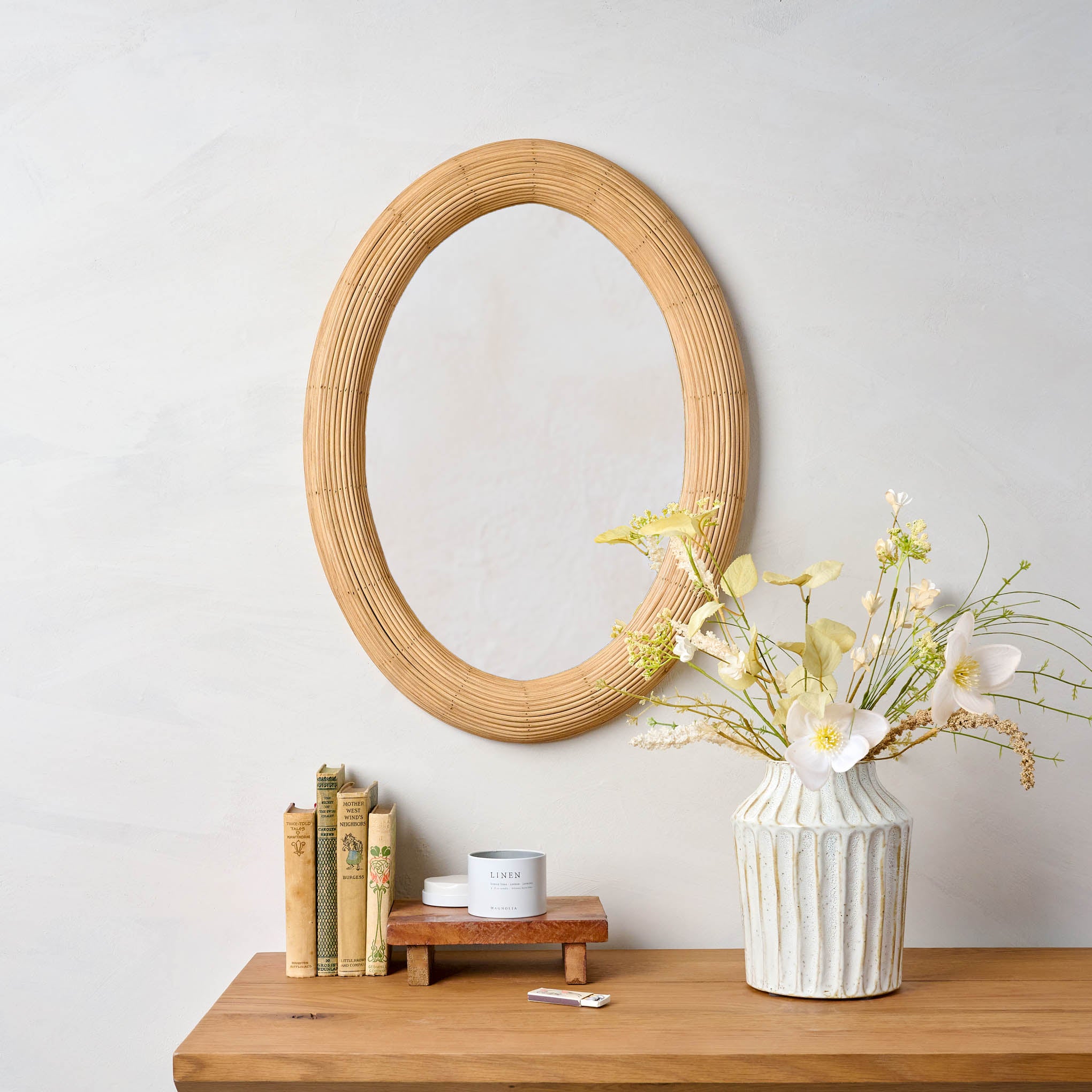 Millie Oval Rattan Mirror wall above a table $128.00