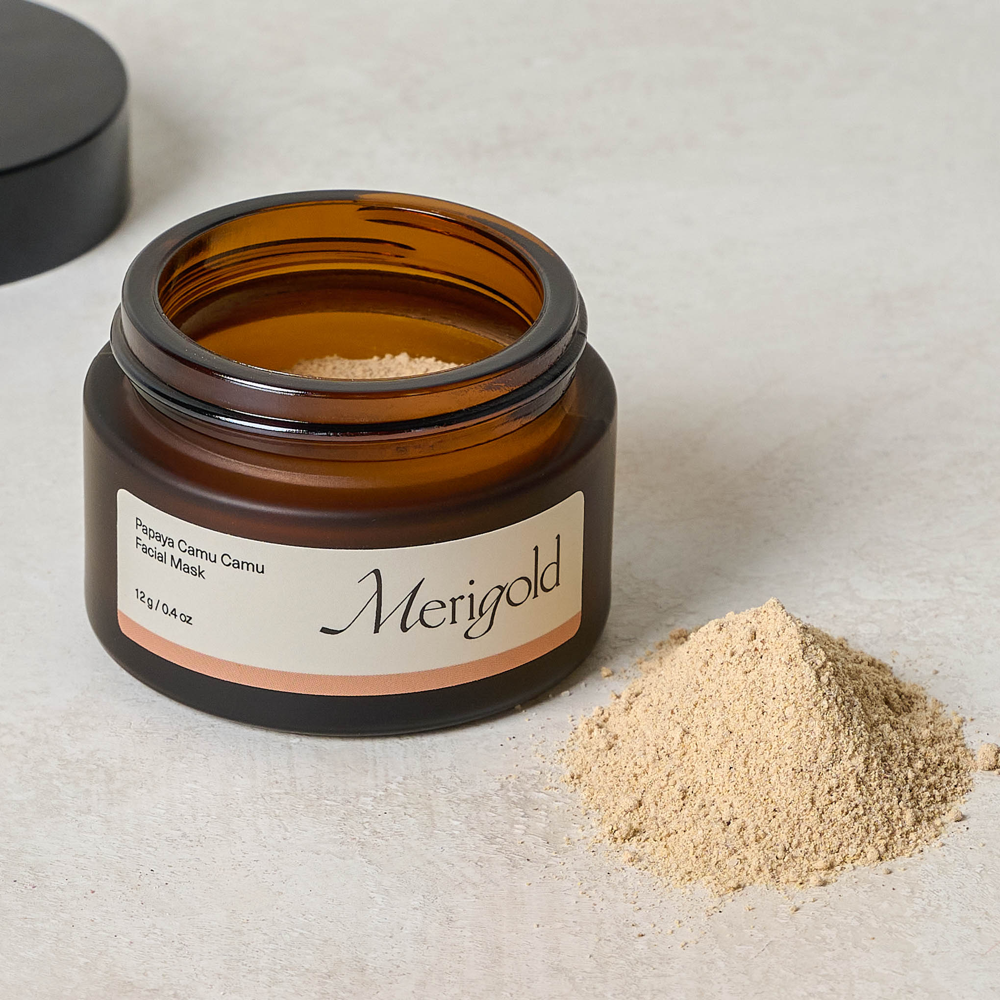 Merigold Papaya Camu Camu Facial Mask jar with top off next to face mask powder