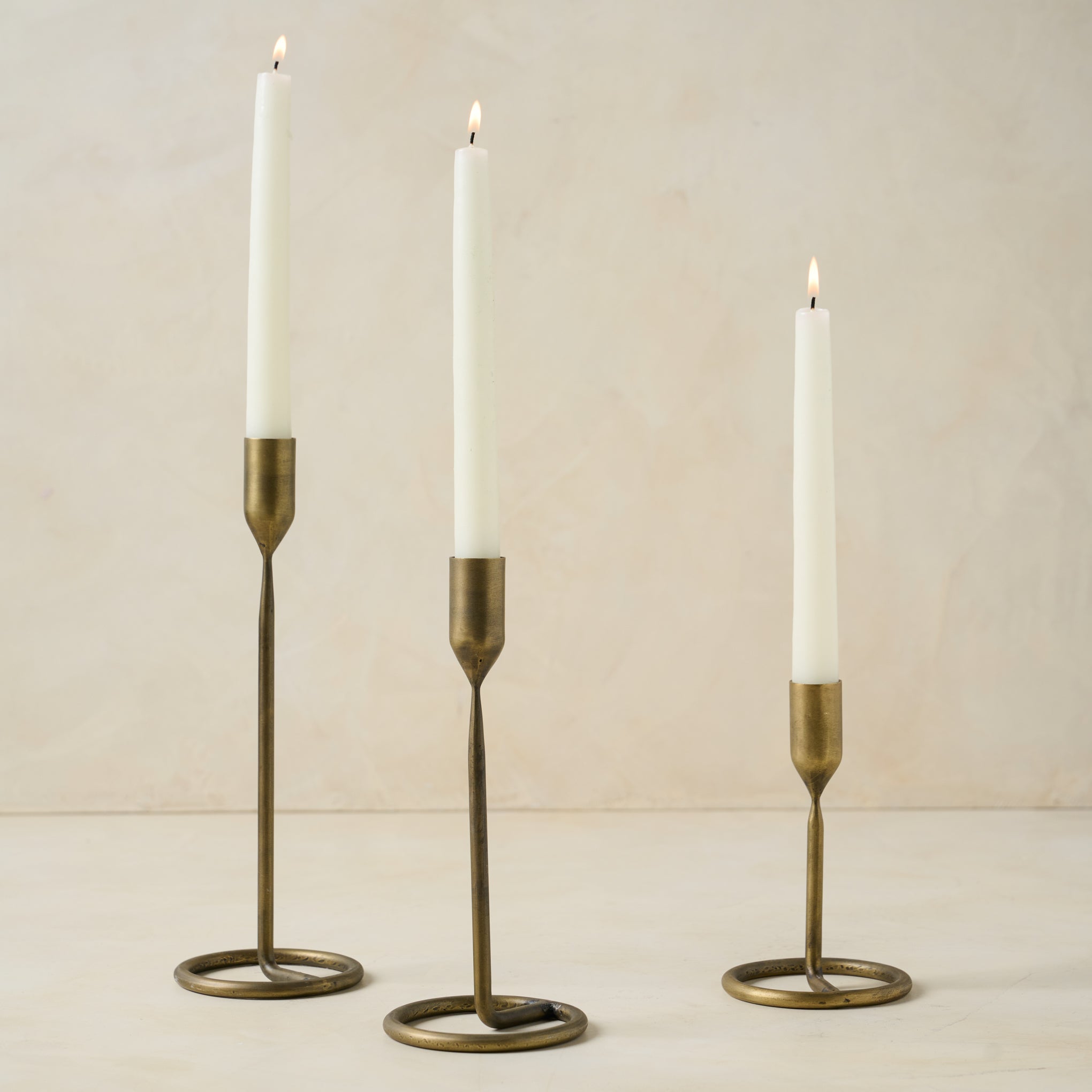 Brandy Antique Brass Taper Holder in tall medium and short sizes containing lit candle sticks On sale for $18.00, discounted from $24.00