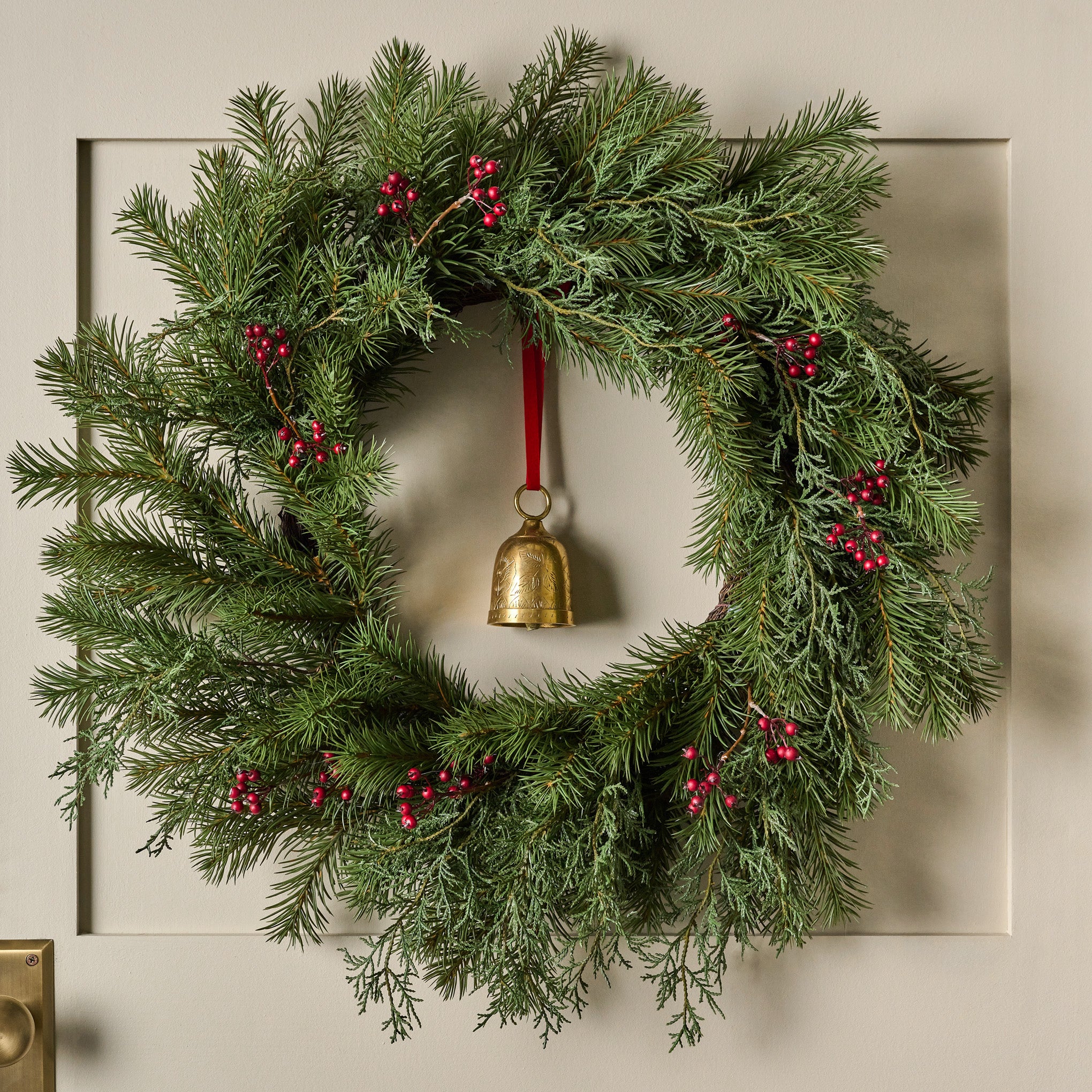 Real Touch Red Berry and Pine Wreath shown hung on door with bell