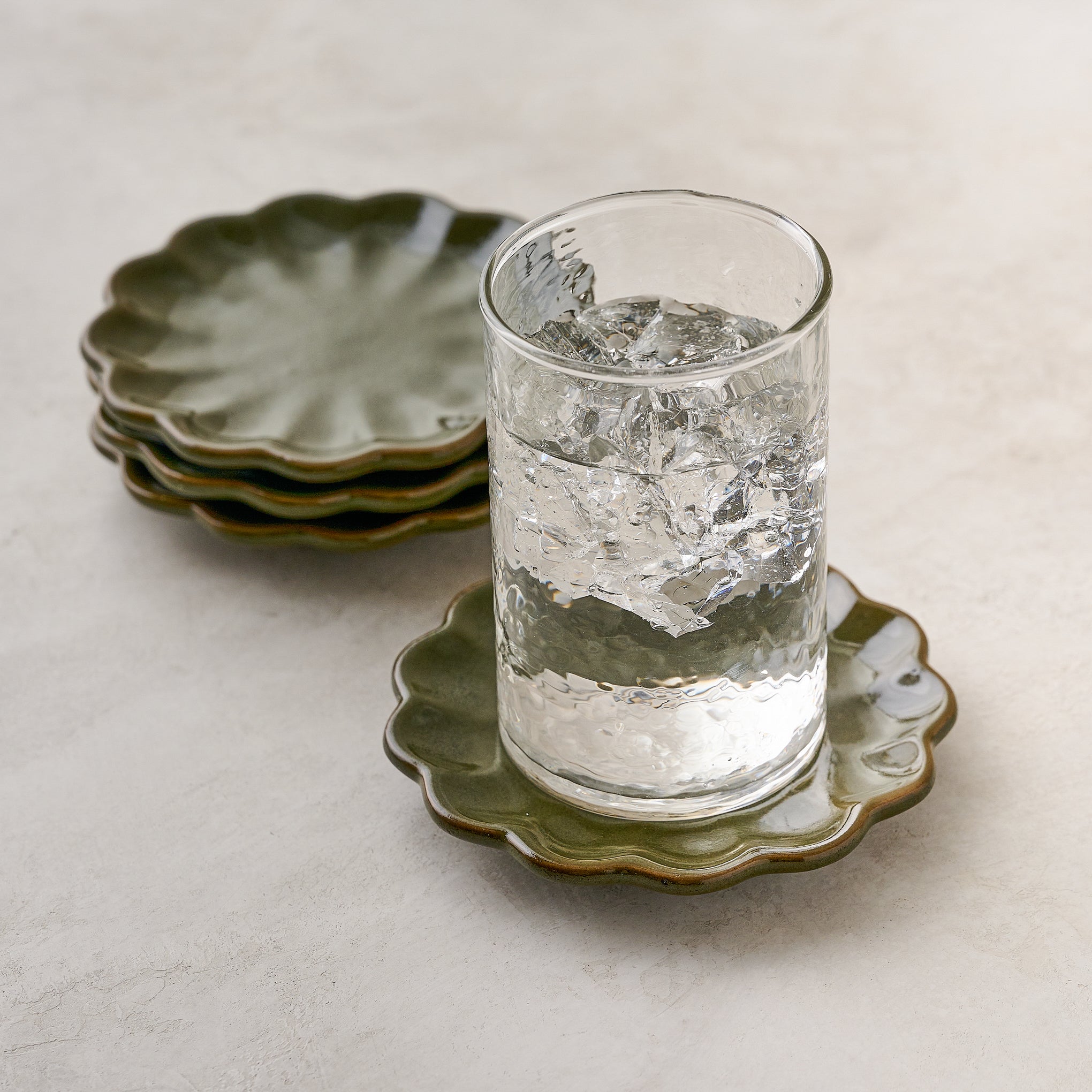 Sage Scalloped Edge Coaster Set of Four shown with glass of water