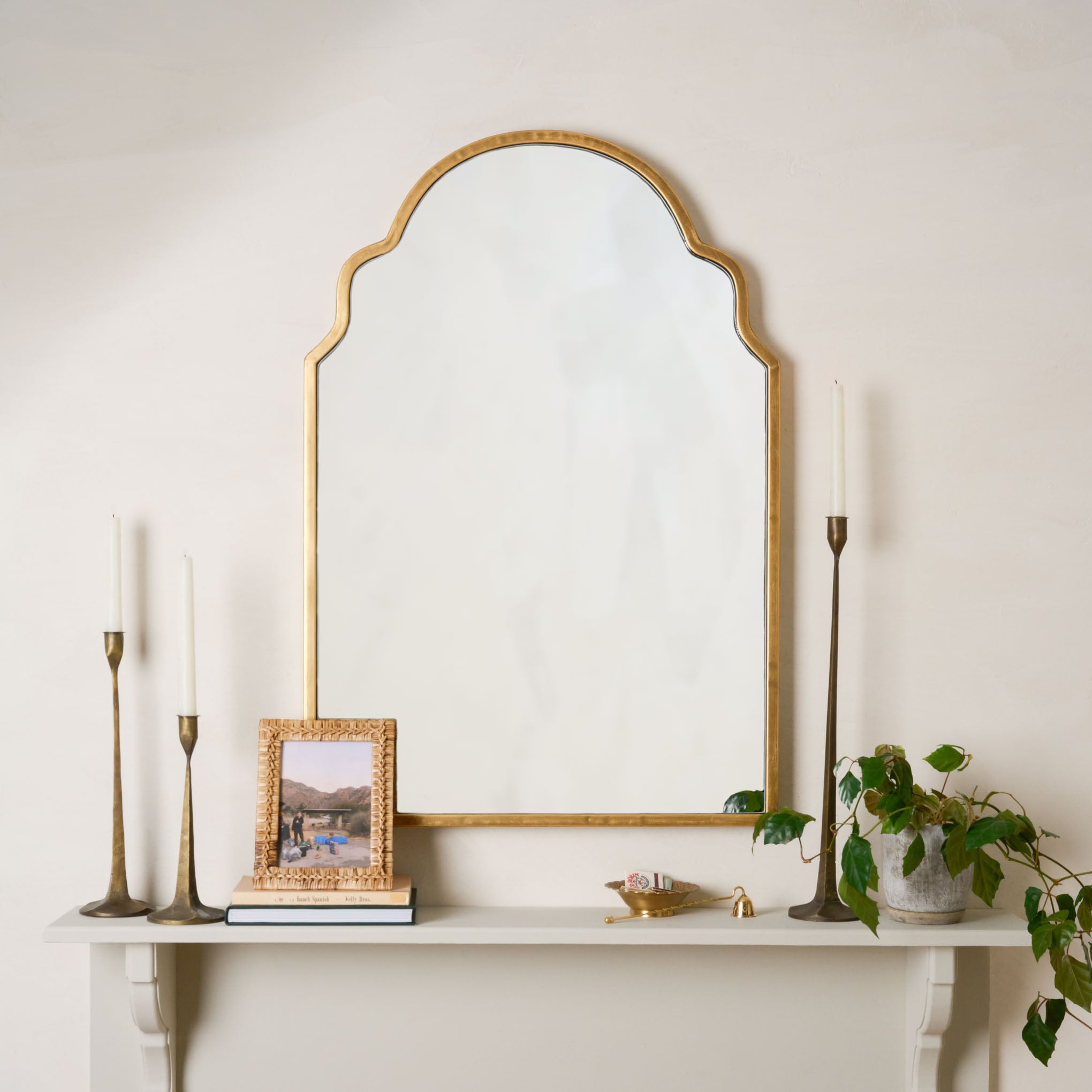 Della Mirror in brass next to taper holders and a rattan photo frame $178.00