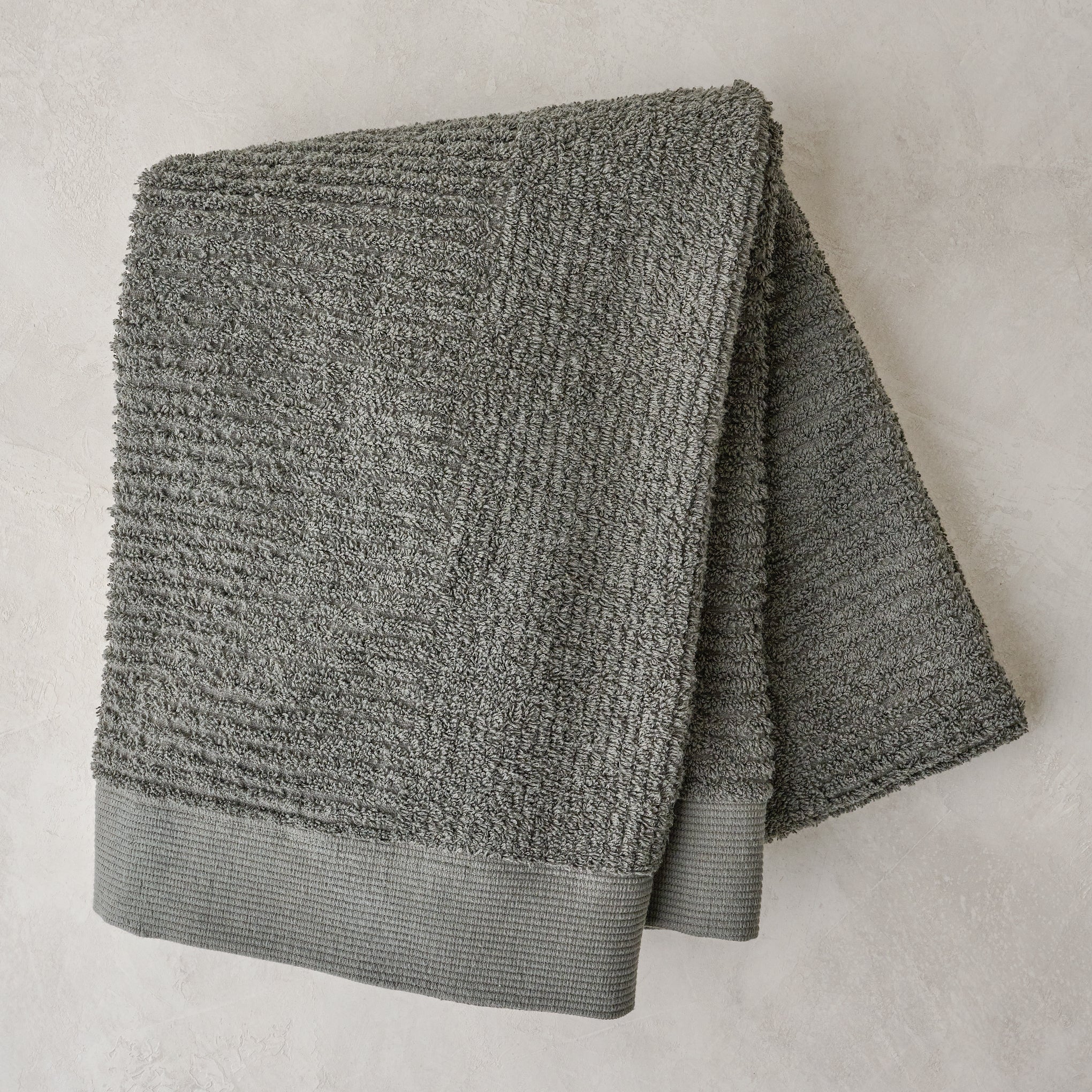 folded olive green textured bath towel