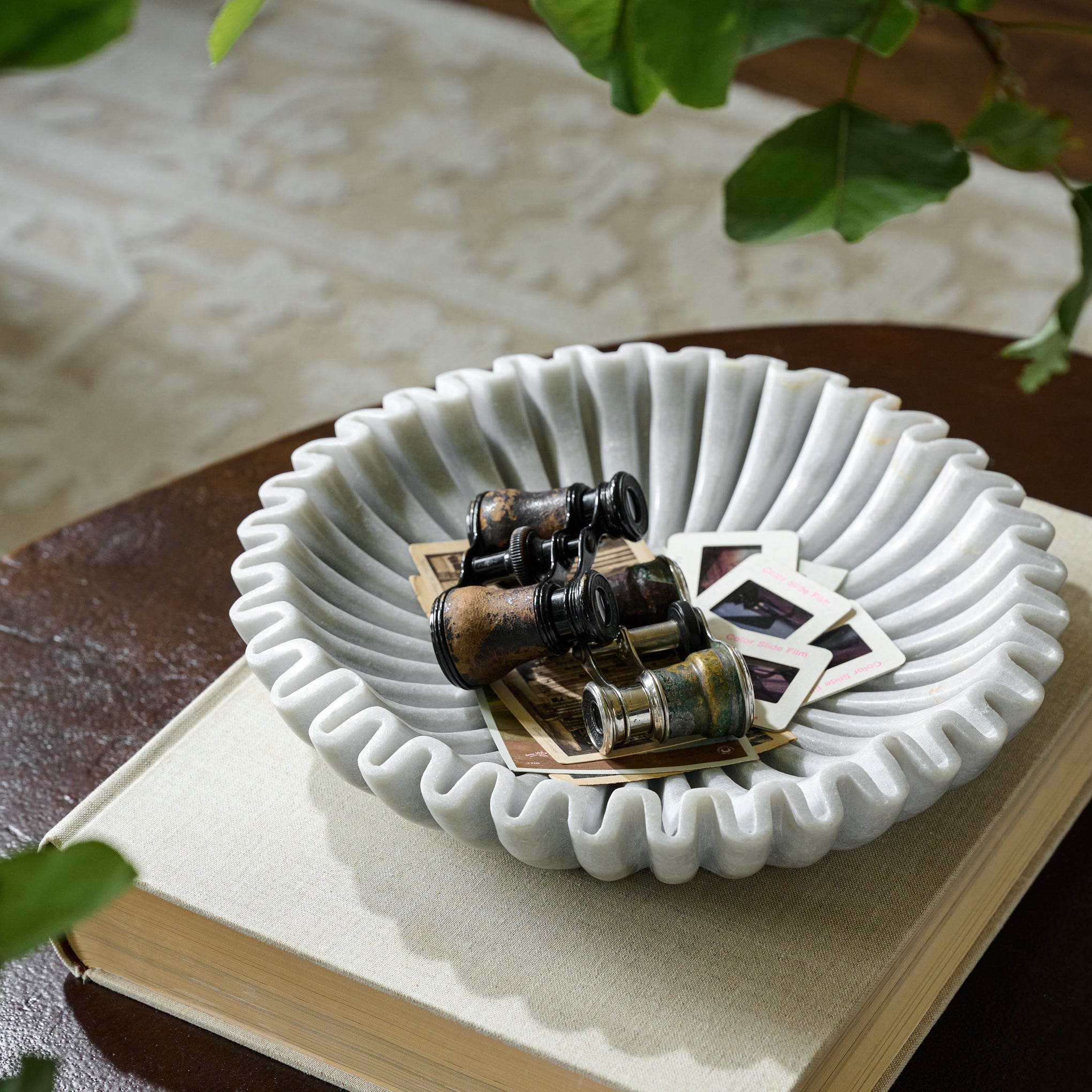 Fluted marble bowl with pictures and binoculars inside. 