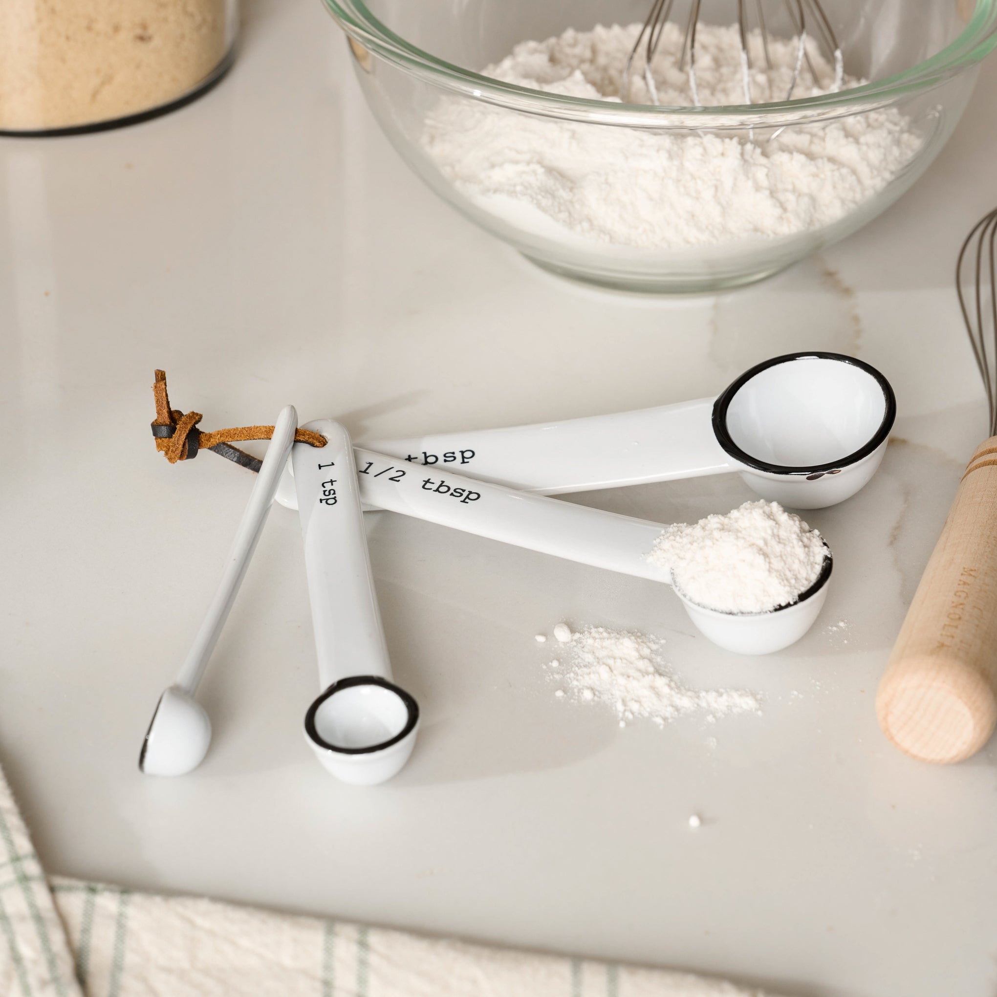 Stoneware Measuring Spoons on counter, one spoon filled with flour