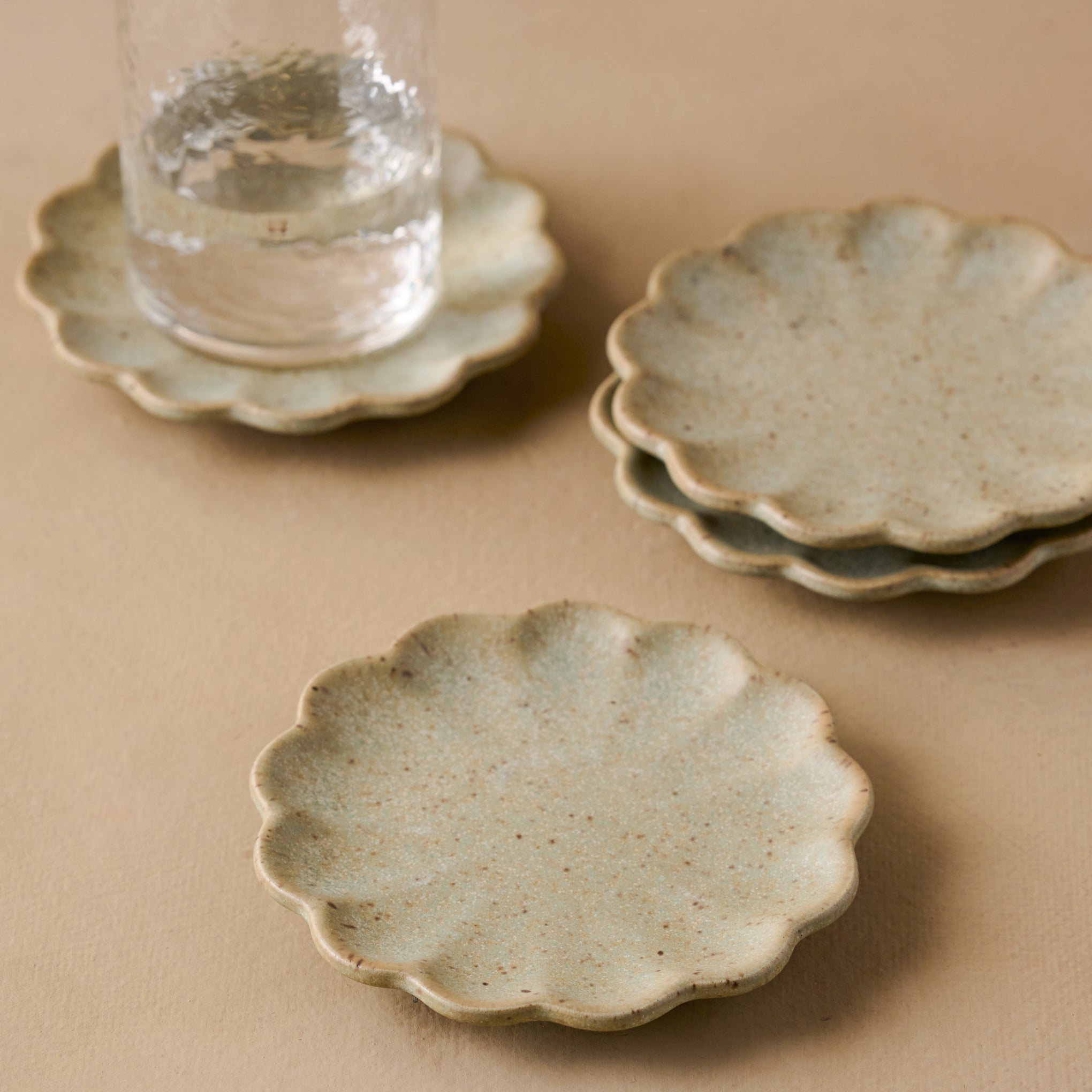 Scalloped Edge Stoneware Coaster Set pictured with rustic glass on coaster $28.00