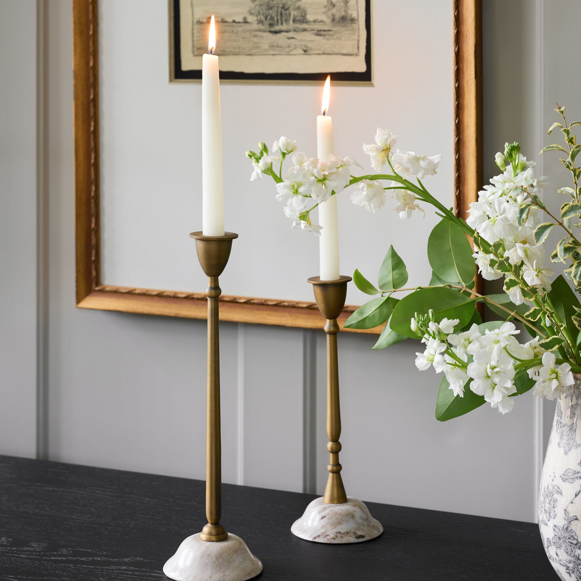 Brass and Marble Candleholder on sideboard next to a vase with florals On sale with items ranging from $25.20 to $27.60, discounted from $42.00 to $46.00