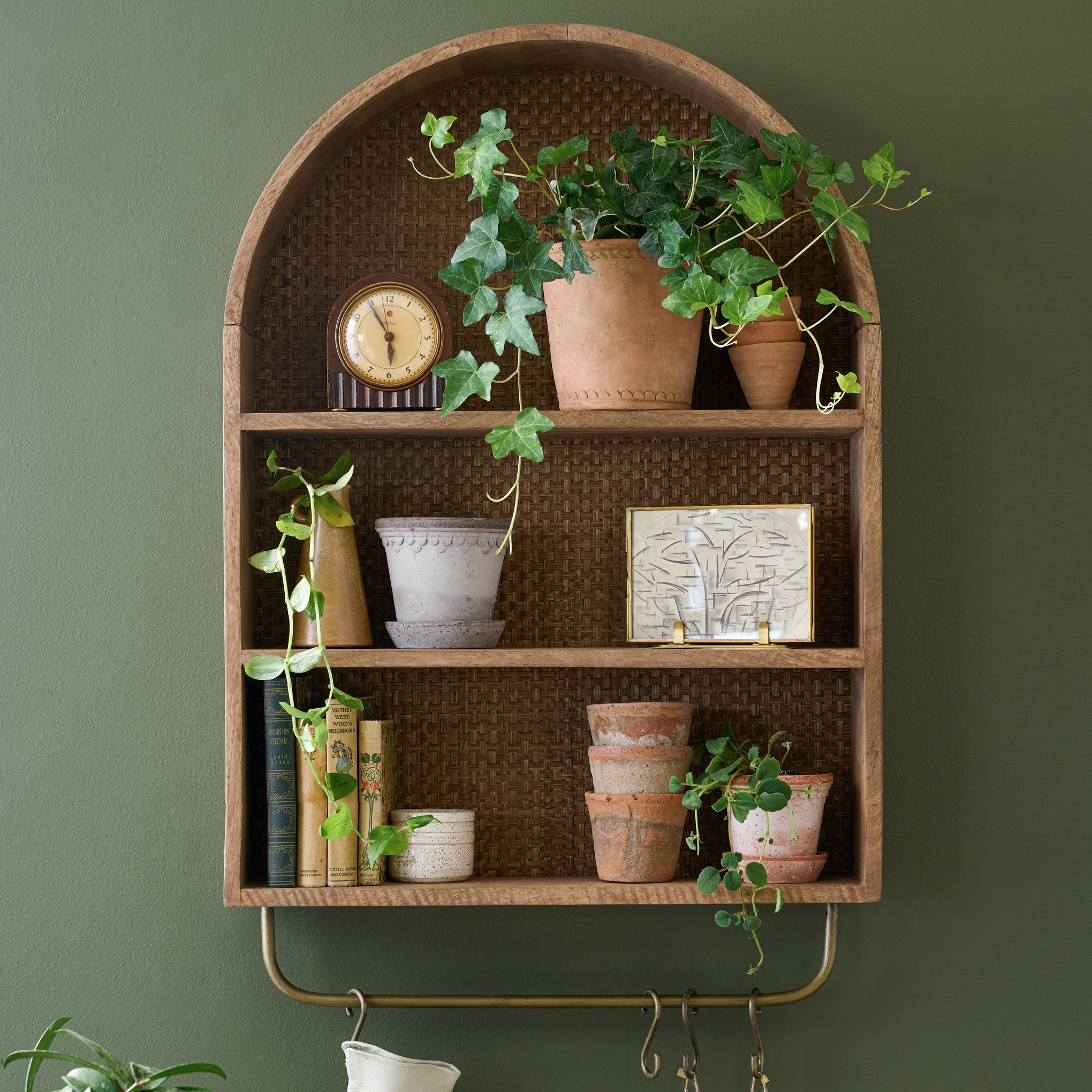 Belmar Arched Woven Wall Shelf with plants and pots and a clock on shelves