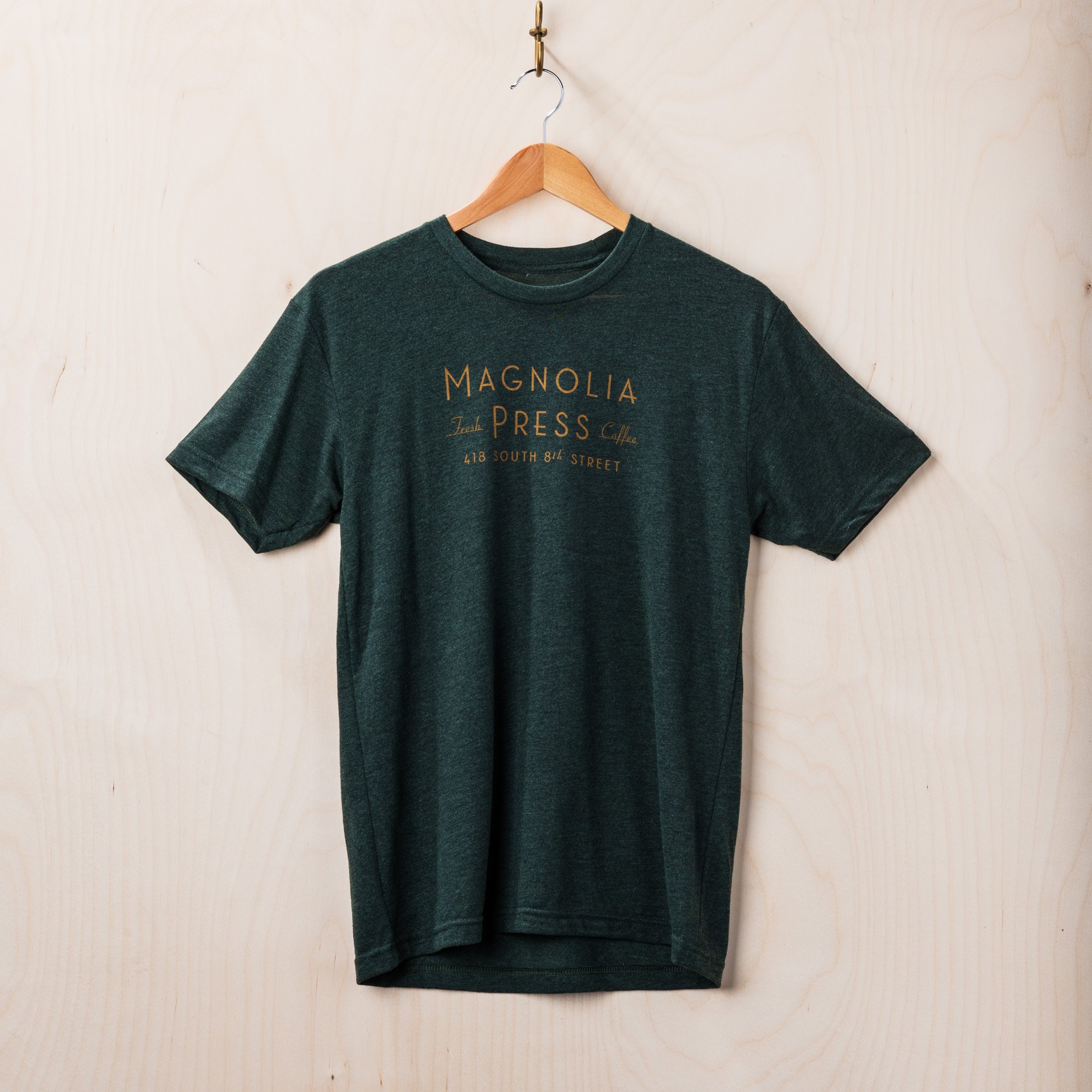 emerald green t-shirt with magnolia press coffee logo in gold across chest