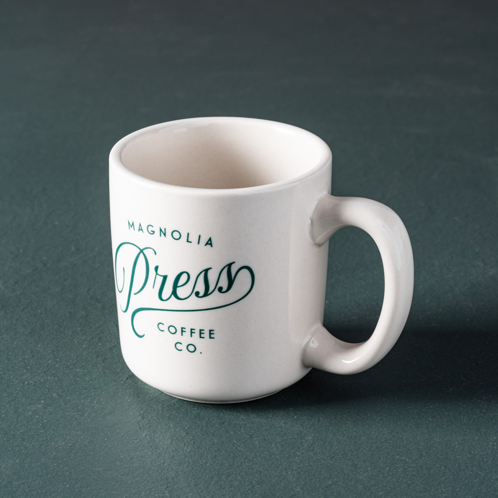 white ceramic coffee mug with Magnolia Press script logo in emerald green $18.00