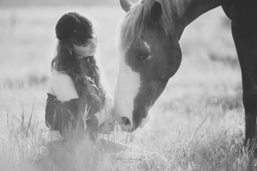 /_vercel/image?url=/Girl+sitting+close+to+her+horse+in+a+meadow.&w=1536&q=100