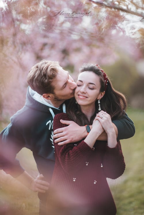 /_vercel/image?url=/Men+is+kissing+his+girlfriend+in+the+cheek+and+behind+them+is+blossoming+sakura+tree.&w=1536&q=100