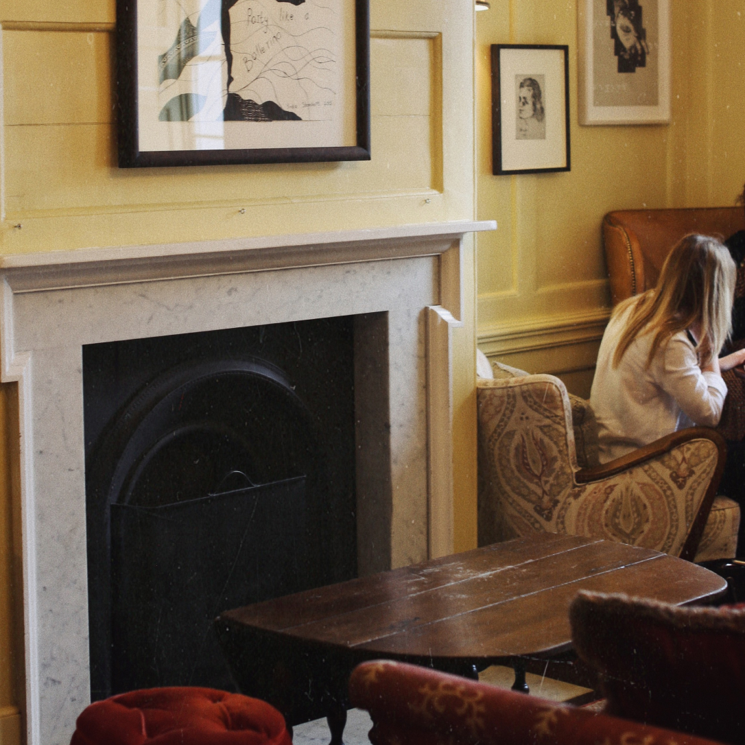 A fireplace in a yellow room with a person sat next to it.