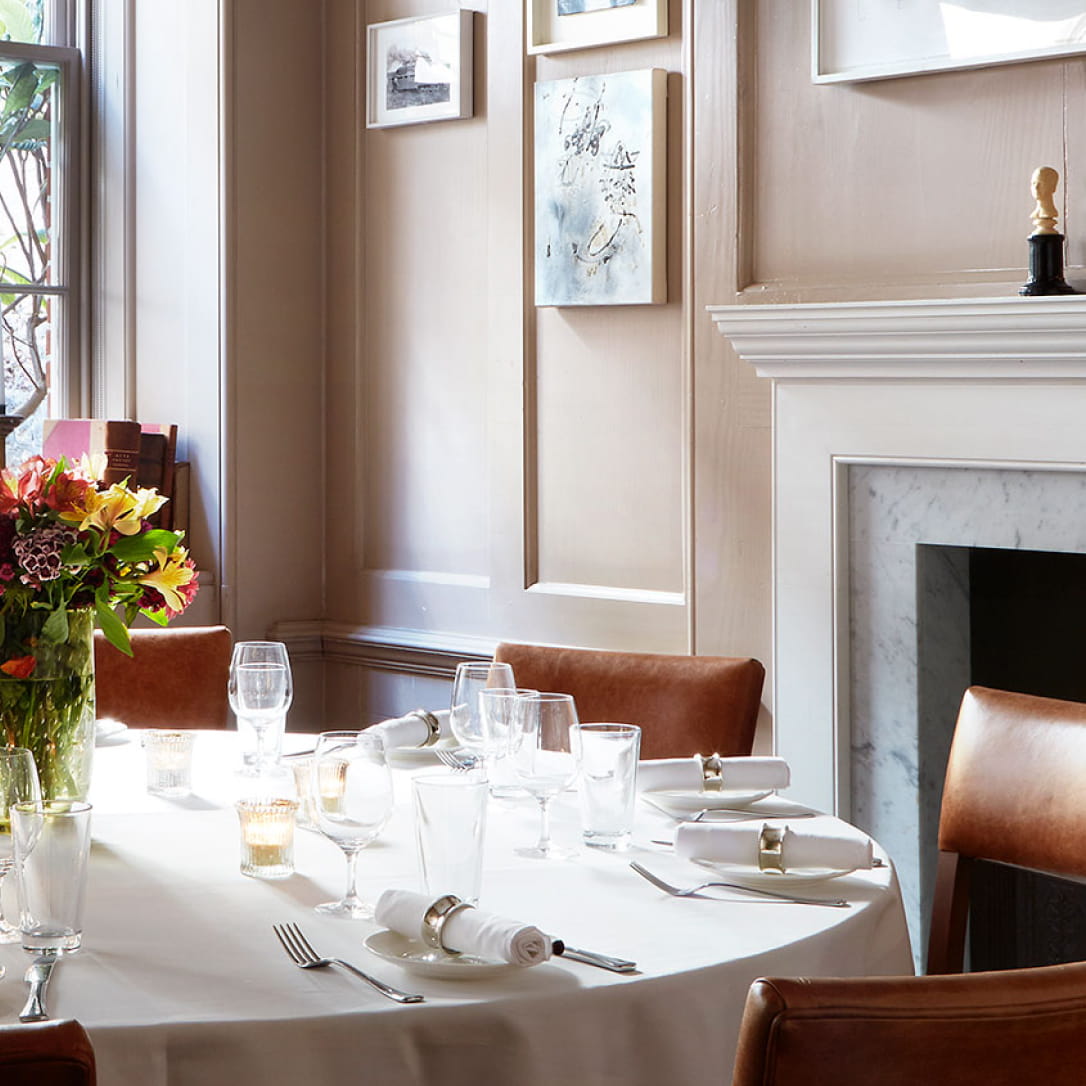A round table laid out for a formal dinner in a small room.