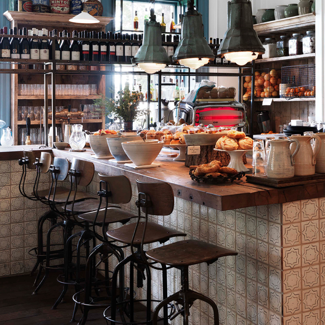 A breakfast bar with high chairs and food on the surface.