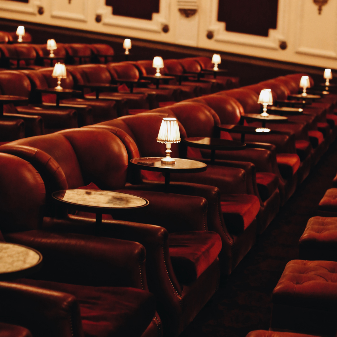 Rows of red cinema armchairs with side tables and lamps.