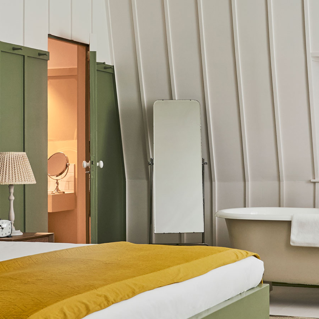 A large bedroom with a roll top bath in it.
