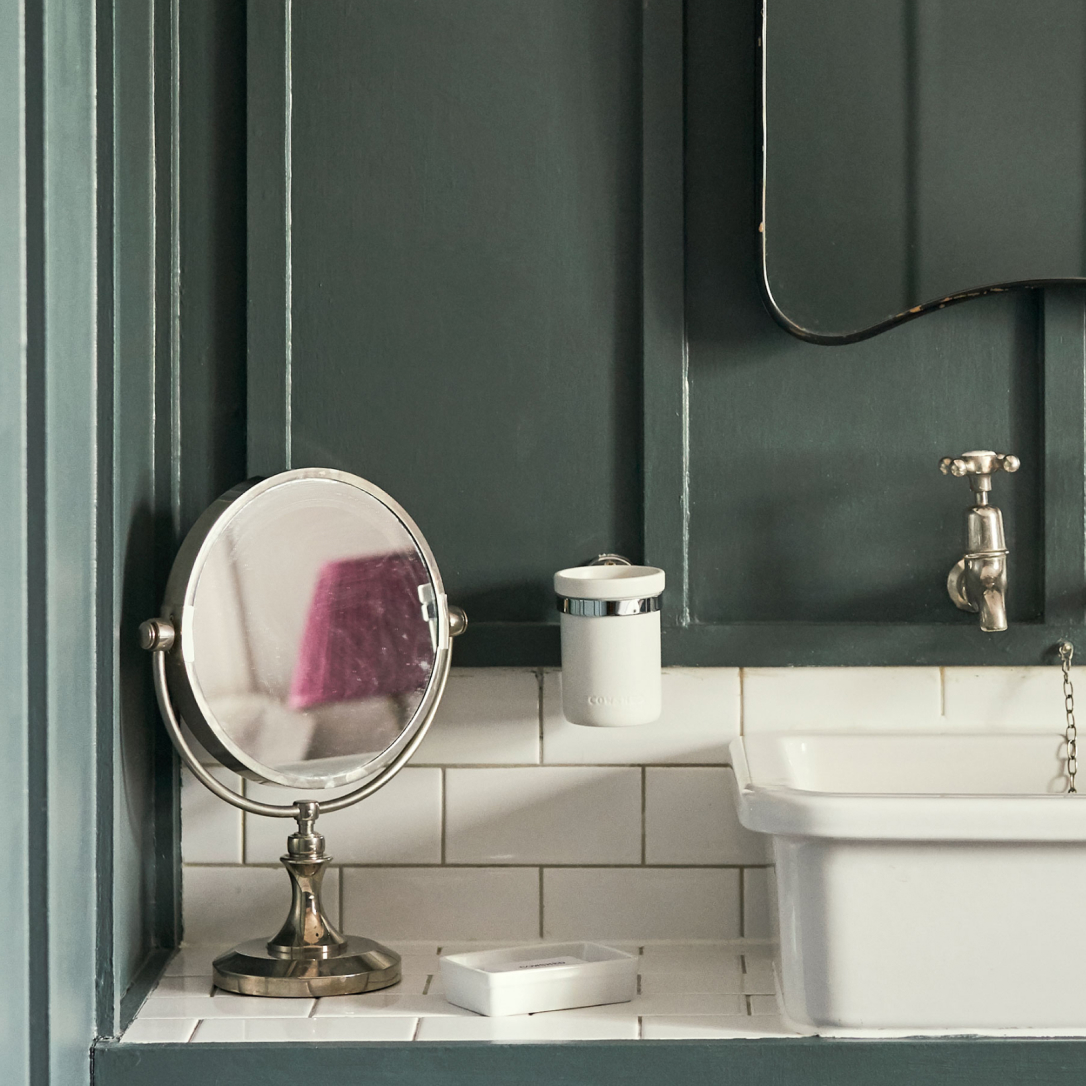 A detail of a washing basin with a mirror in a bathroom.
