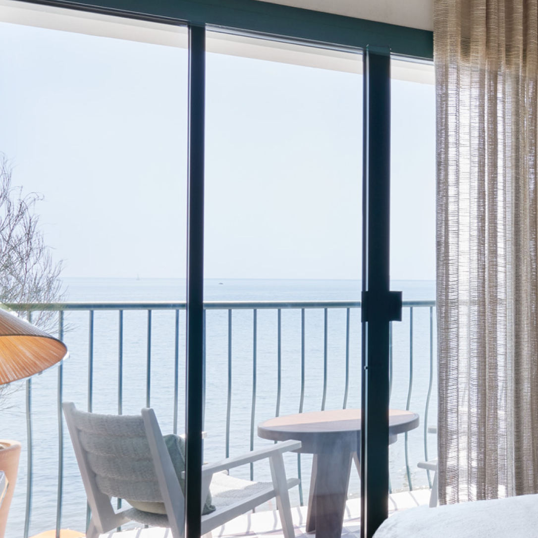 Sliding doors leading onto a bedroom balcony overlooking the sea.