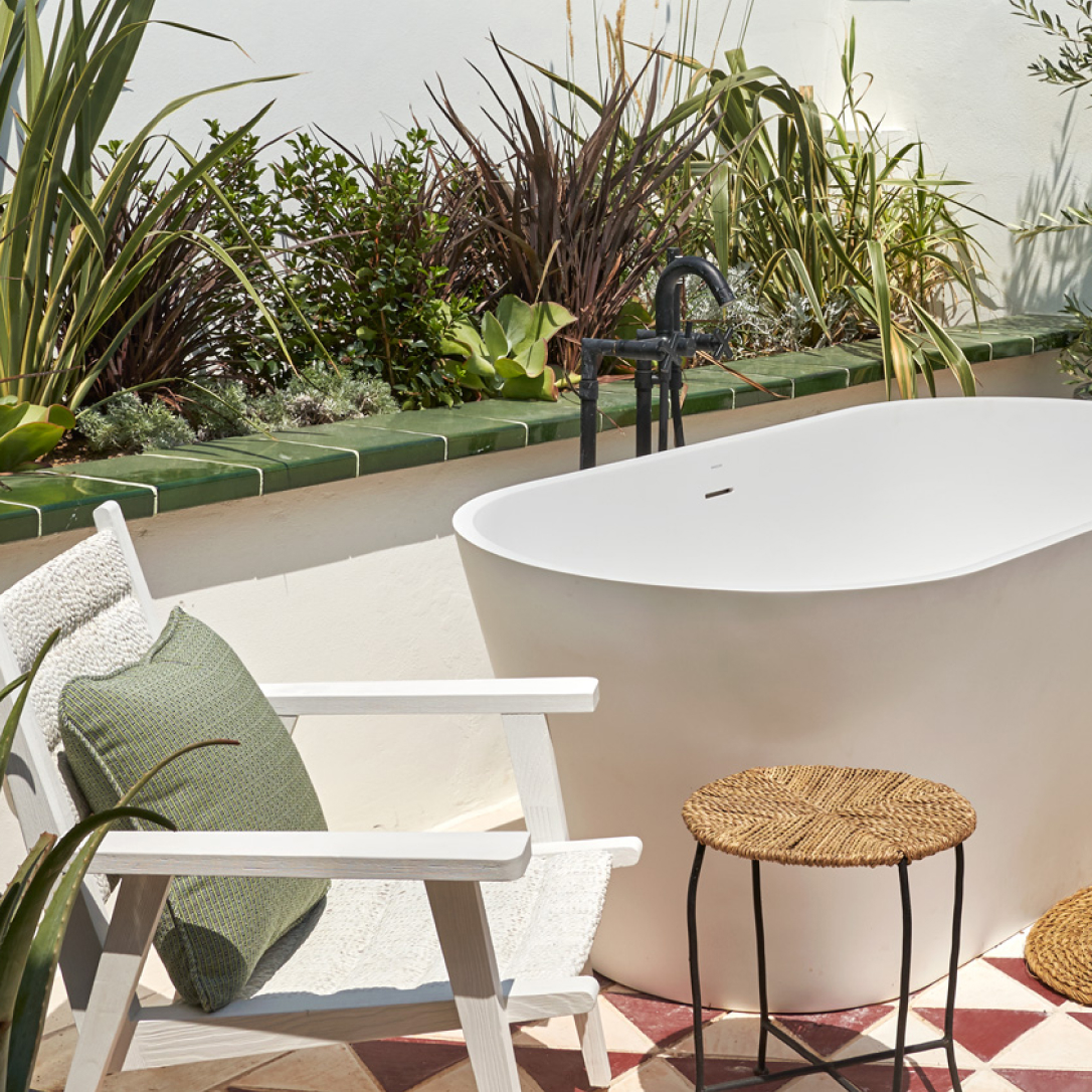 An outdoor terrace with a chair and a bathtub on it.