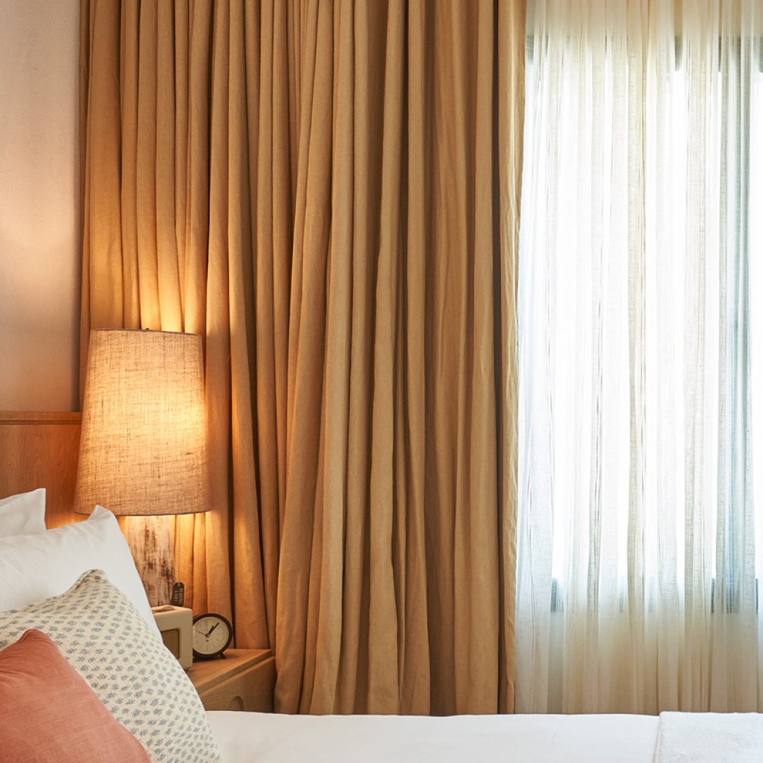 A bed next to a window with drawn curtains.