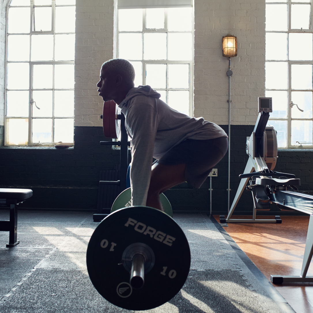 A man lifts a large weight in a gym.