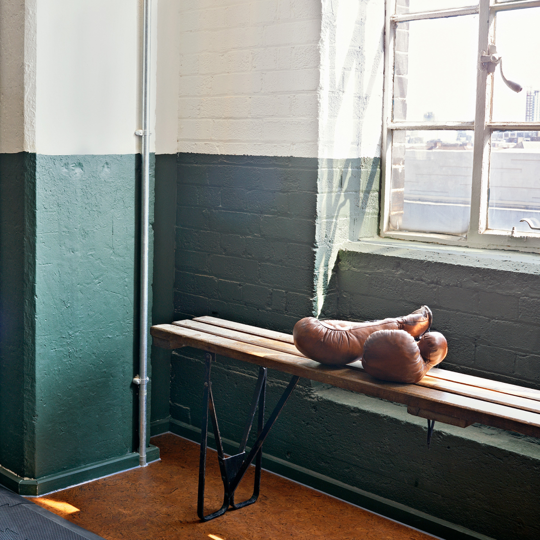 A pair of leather boxing gloves on a bench.