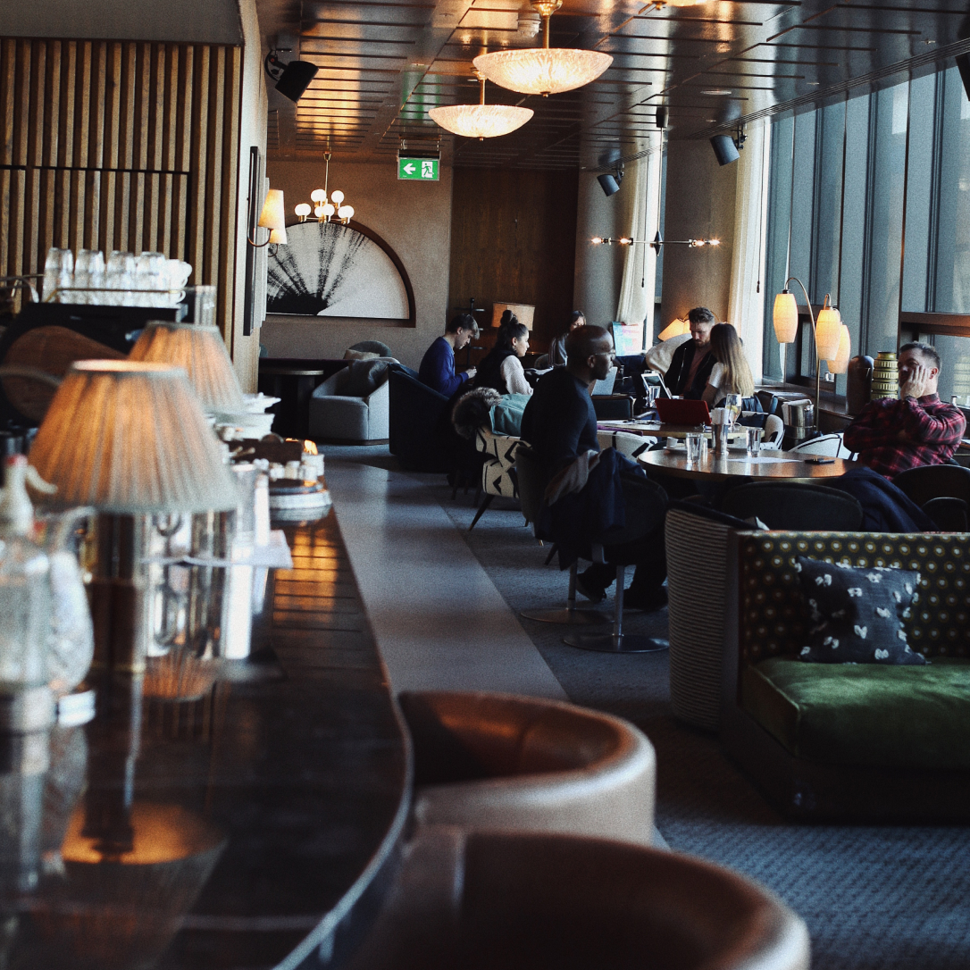 People sit and chat in the background of a bar and lounge-like interior.