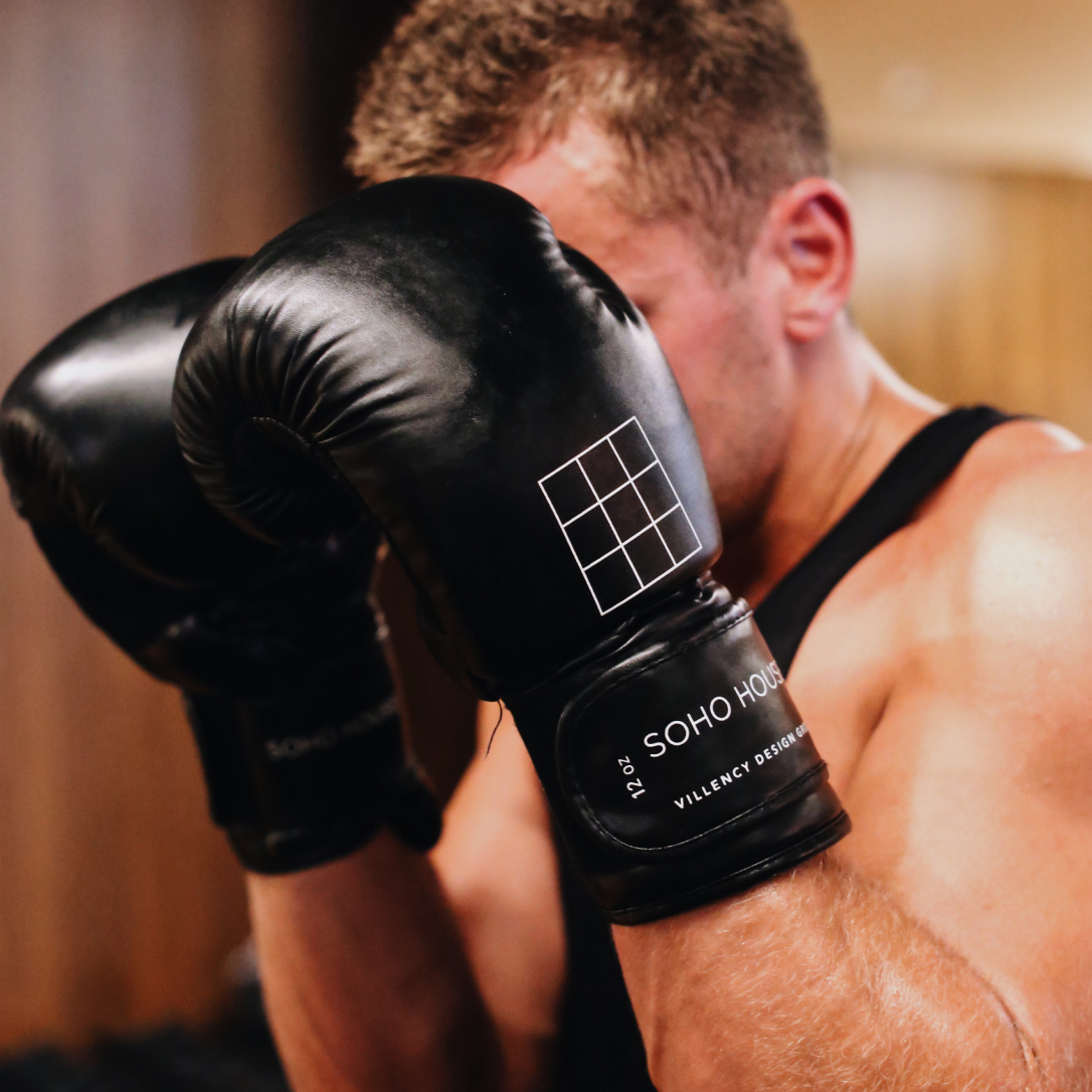 A man shields his face with boxing gloves.