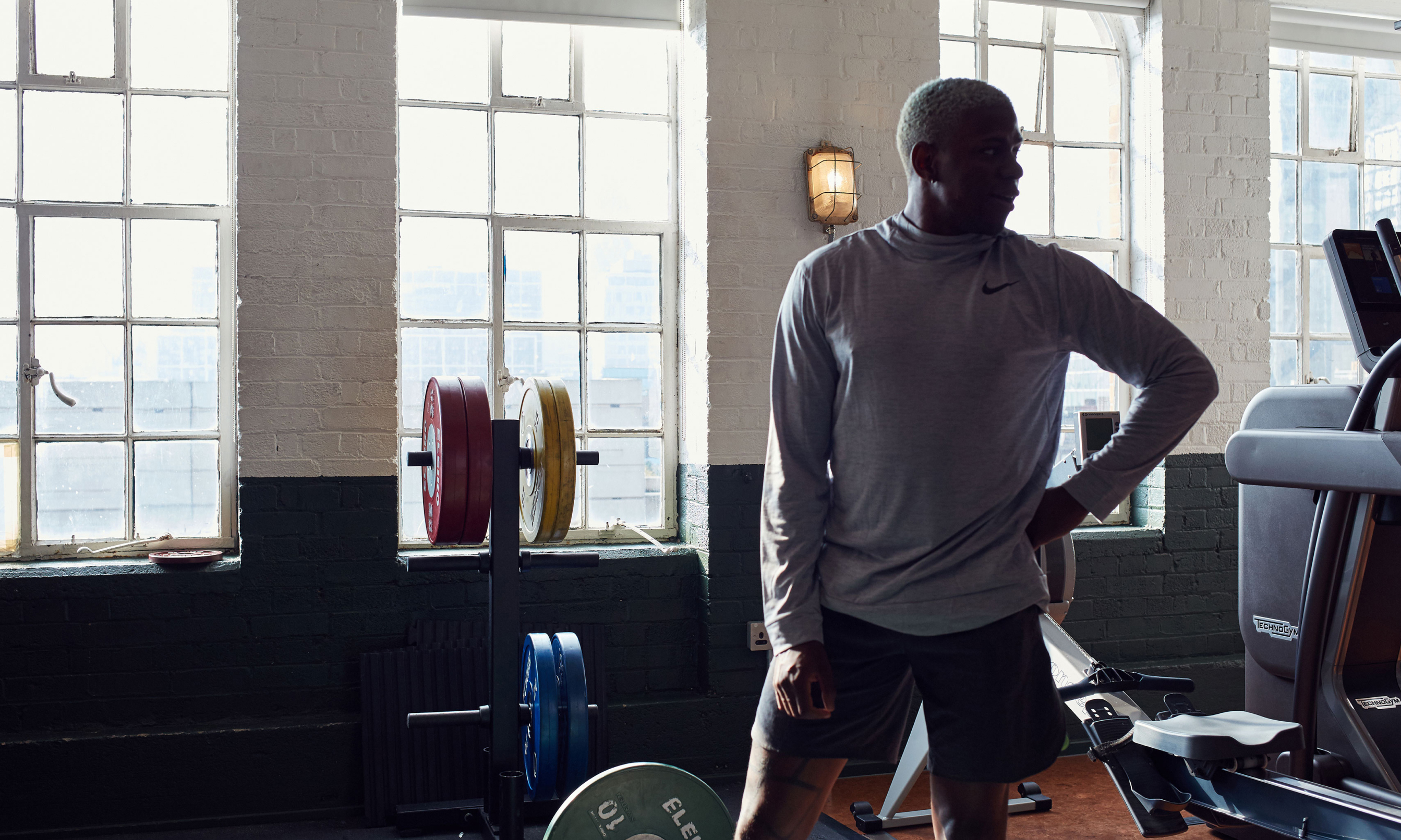 A man standing in a gym surrounded by weights.
