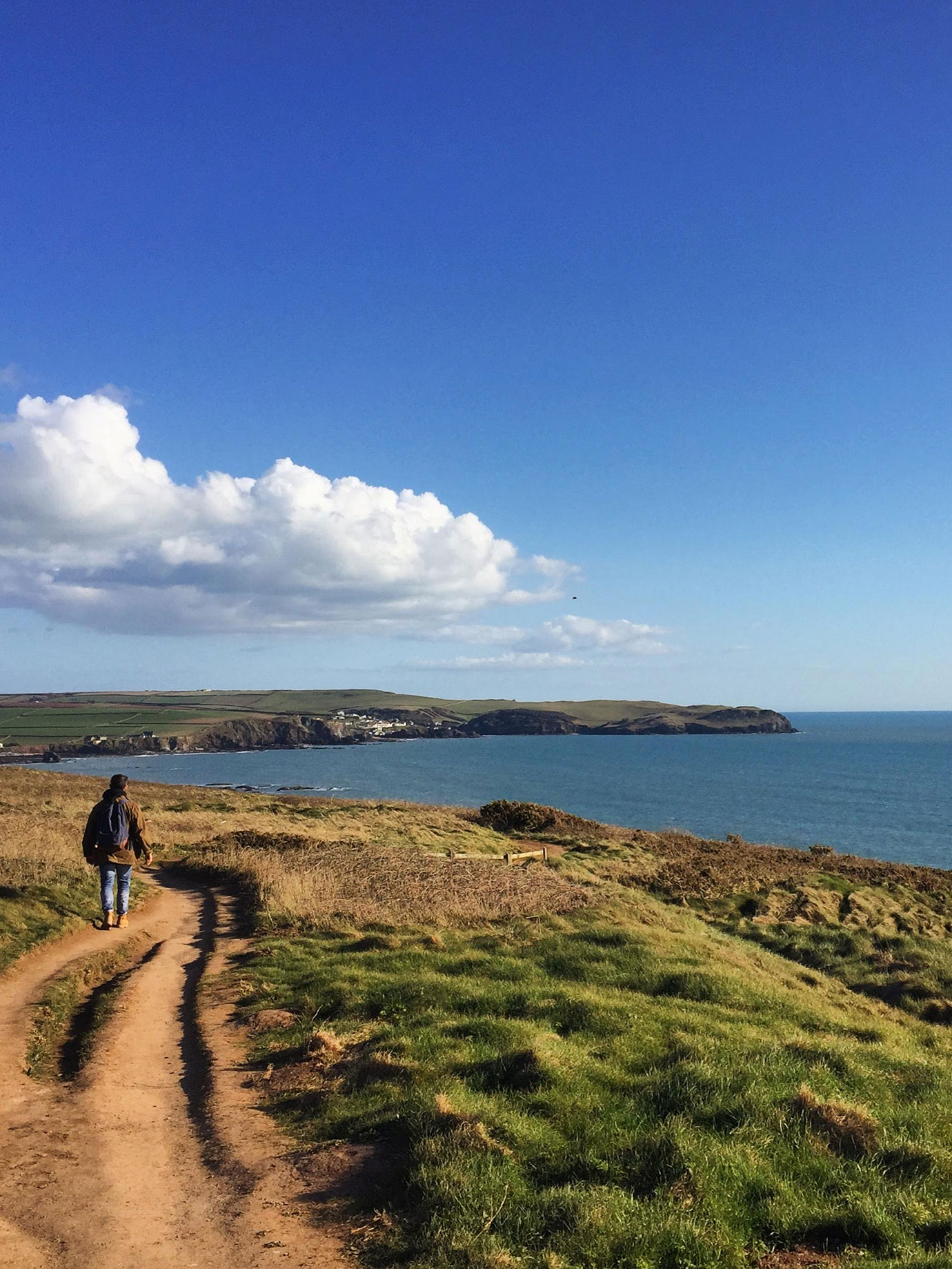 A person walking on a clifftop path by the sea.