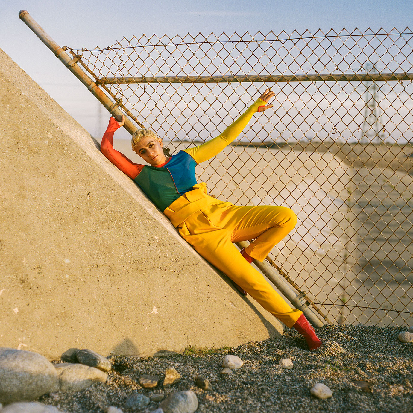 A woman wearing colourful clothing leaning against a concrete wall.
