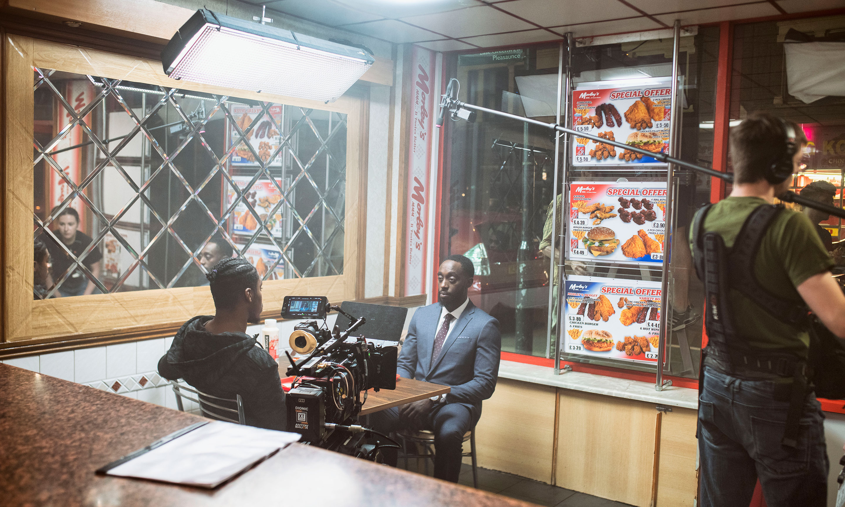 Two men sitting at a table in a chicken shop film set.