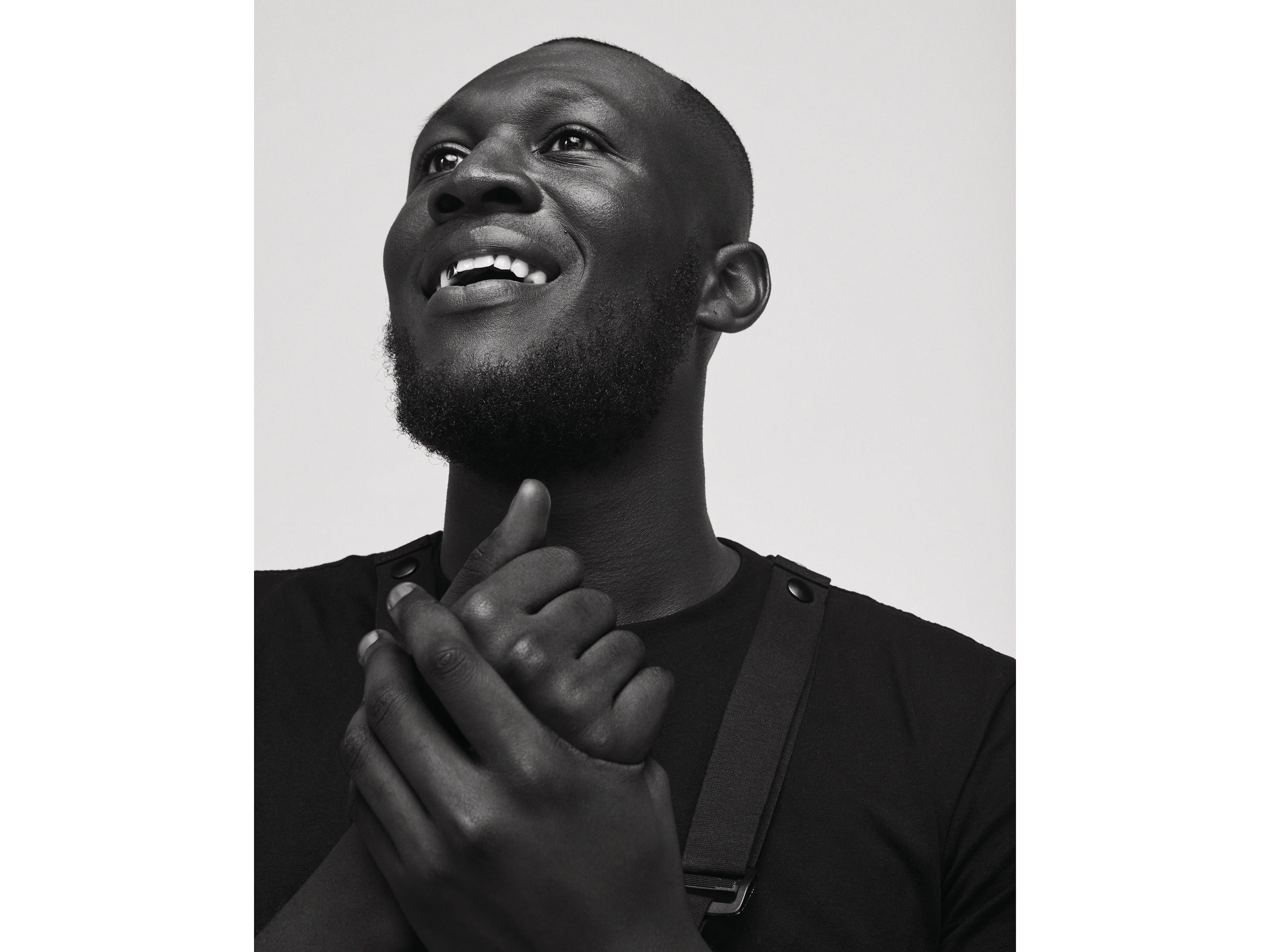 A man smiling while holding his hands.
