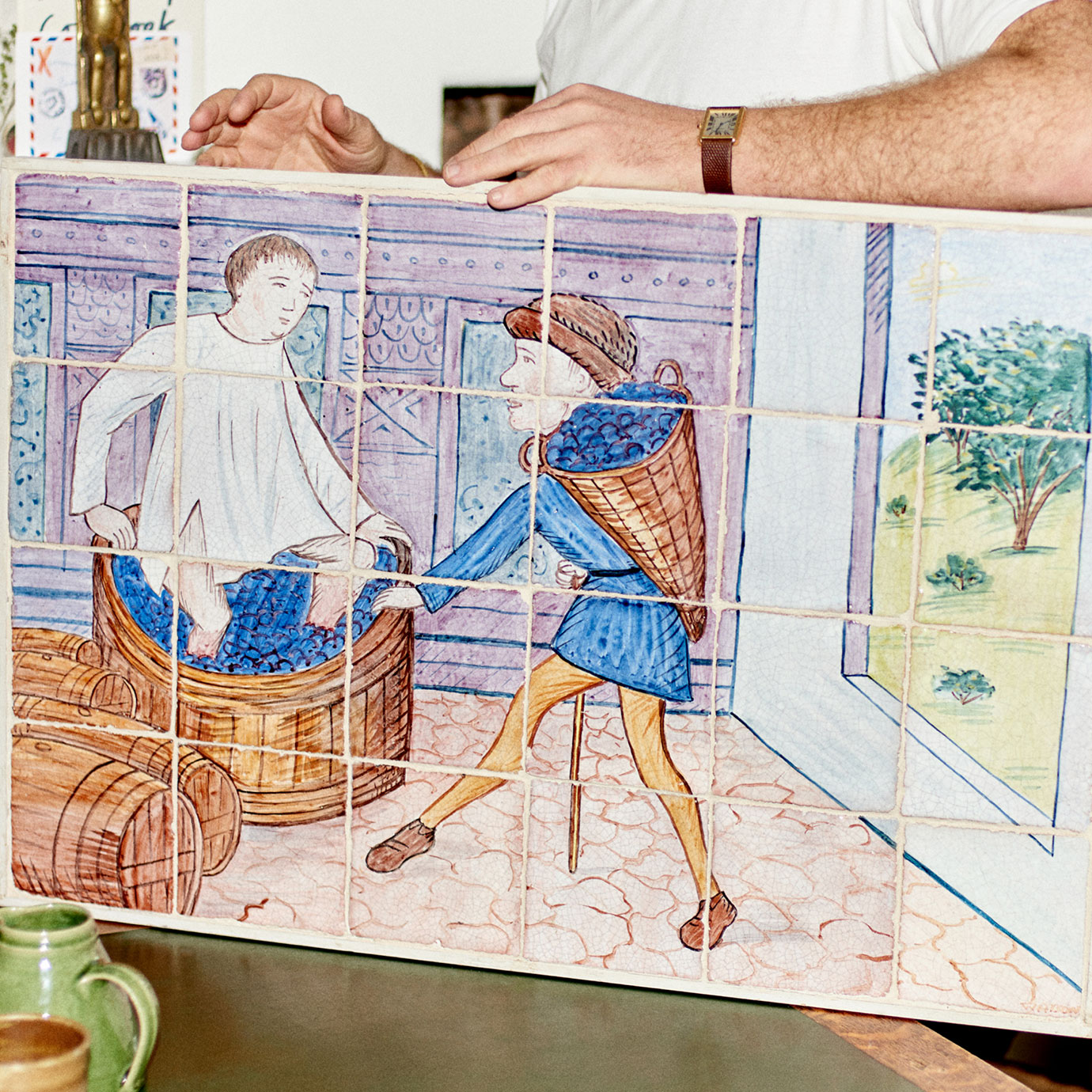 A man holding a painting on tiles.